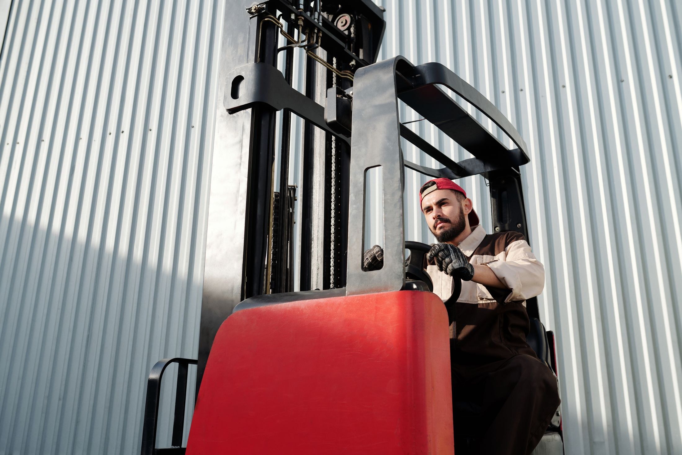 Forklift operator beside a corrugated warehouse wall
